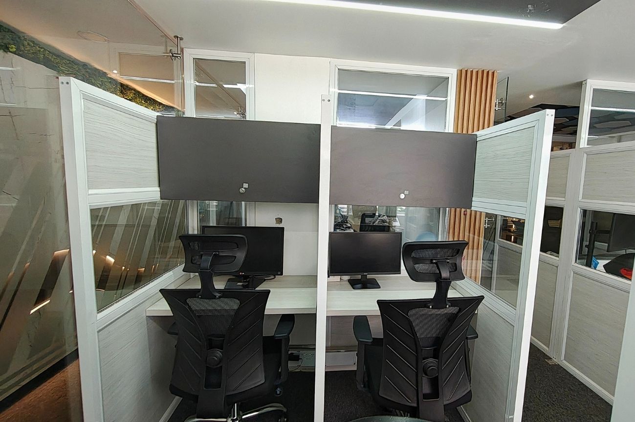 Cubículos individuales de Hot Desk en Coworking Marbella con escritorios, monitores y sillas ergonómicas, ofreciendo privacidad y concentración en Bogotá.