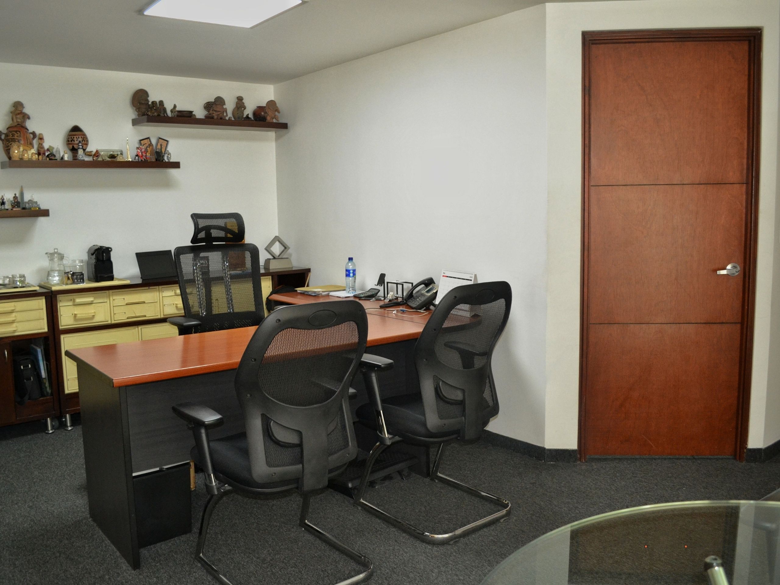 Oficina compartida o ejecutiva en Coworking Marbella con dos puestos de trabajo, escritorios, sillas ergonómicas y estantes decorados, ideal para equipos pequeños o colaboradores.