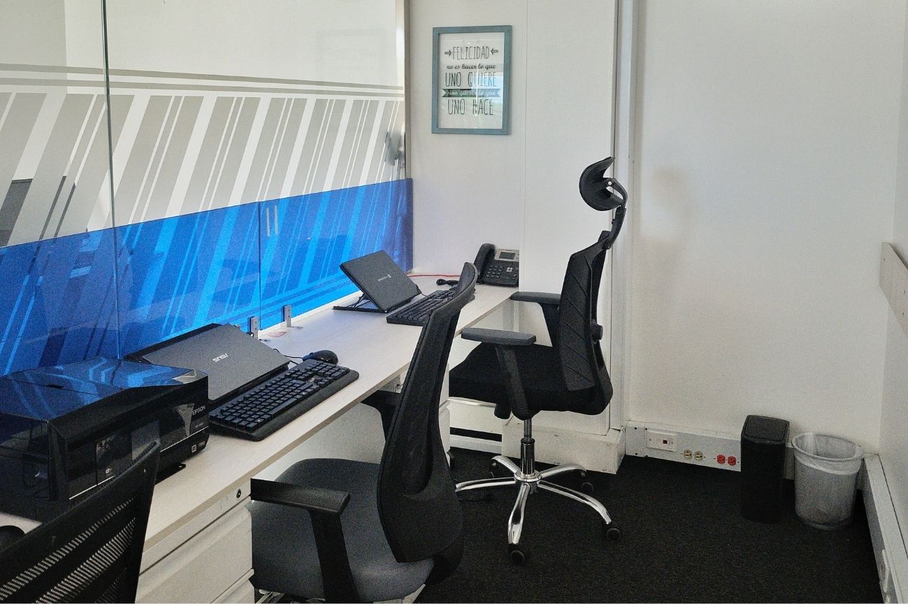 Oficina privada para equipo en Coworking Marbella con múltiples puestos de trabajo, pantallas, sillas ergonómicas y un ambiente propicio para la colaboración en Bogotá.