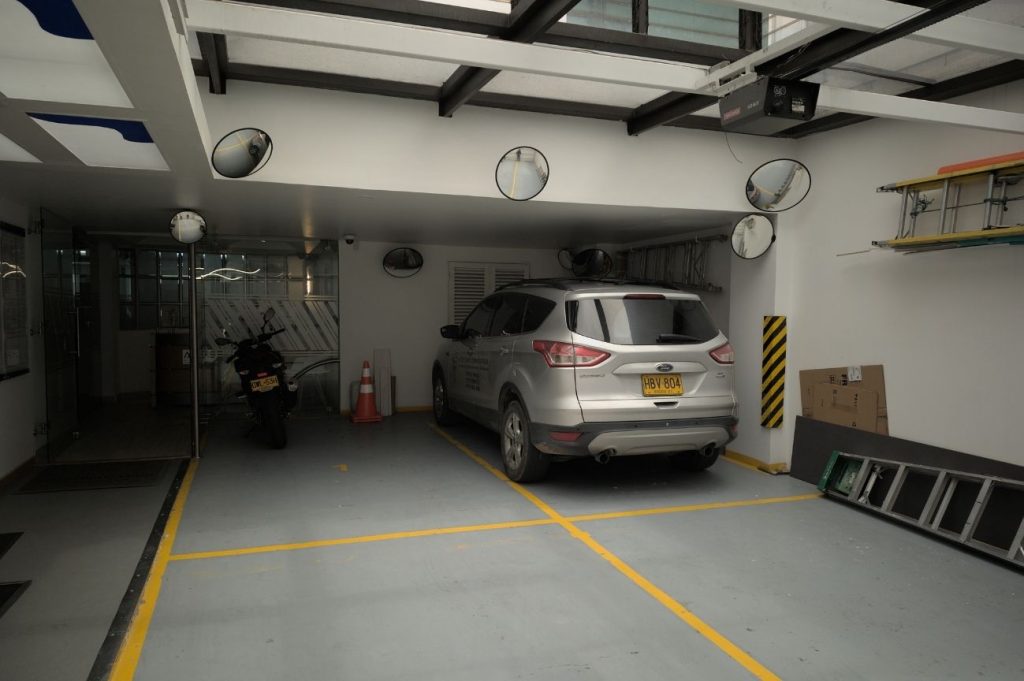 Amplio parqueadero subterráneo en Coworking Marbella con cámaras de seguridad y espejos para maniobras, ofreciendo comodidad y seguridad para vehículos de coworkers y visitantes en Bogotá.