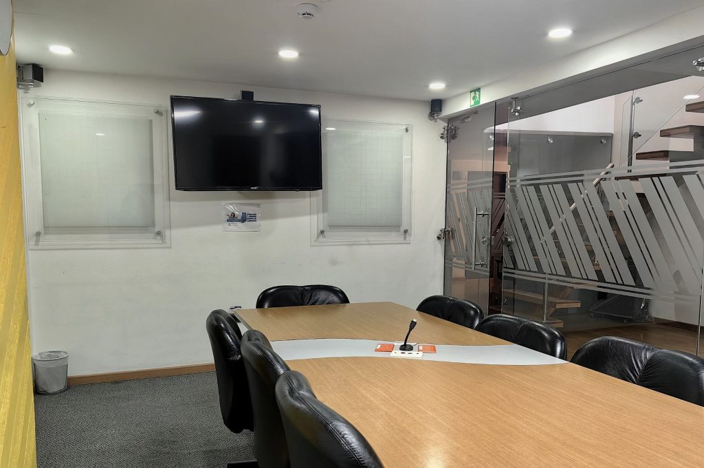 Sala de juntas equipada en Coworking Marbella con mesa, sillas ergonómicas, TV para presentaciones y ambiente profesional en Bogotá.